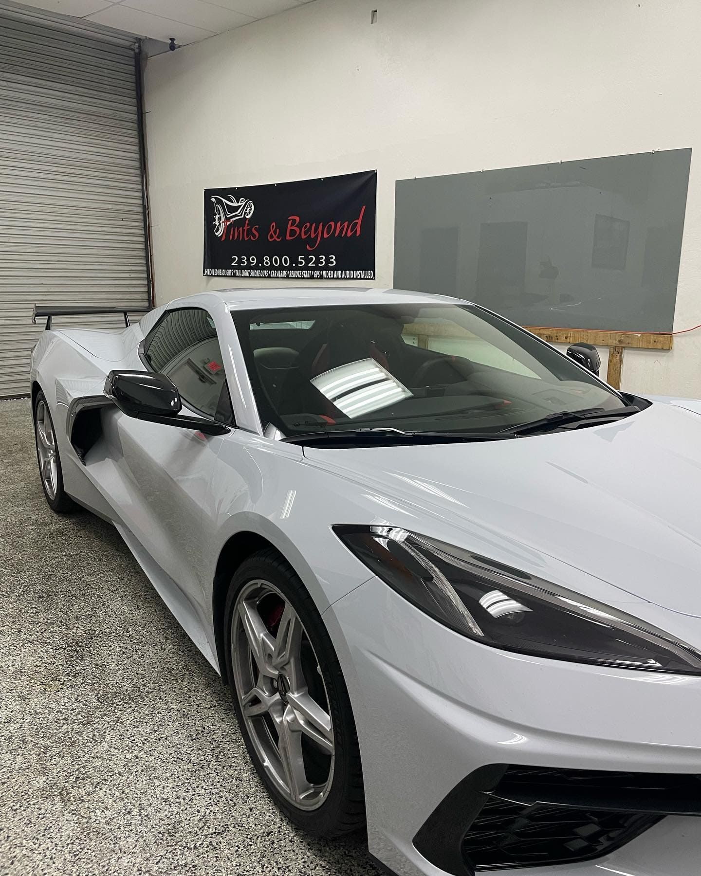 Silver sports car parked indoors in a showroom or garage, front-left view