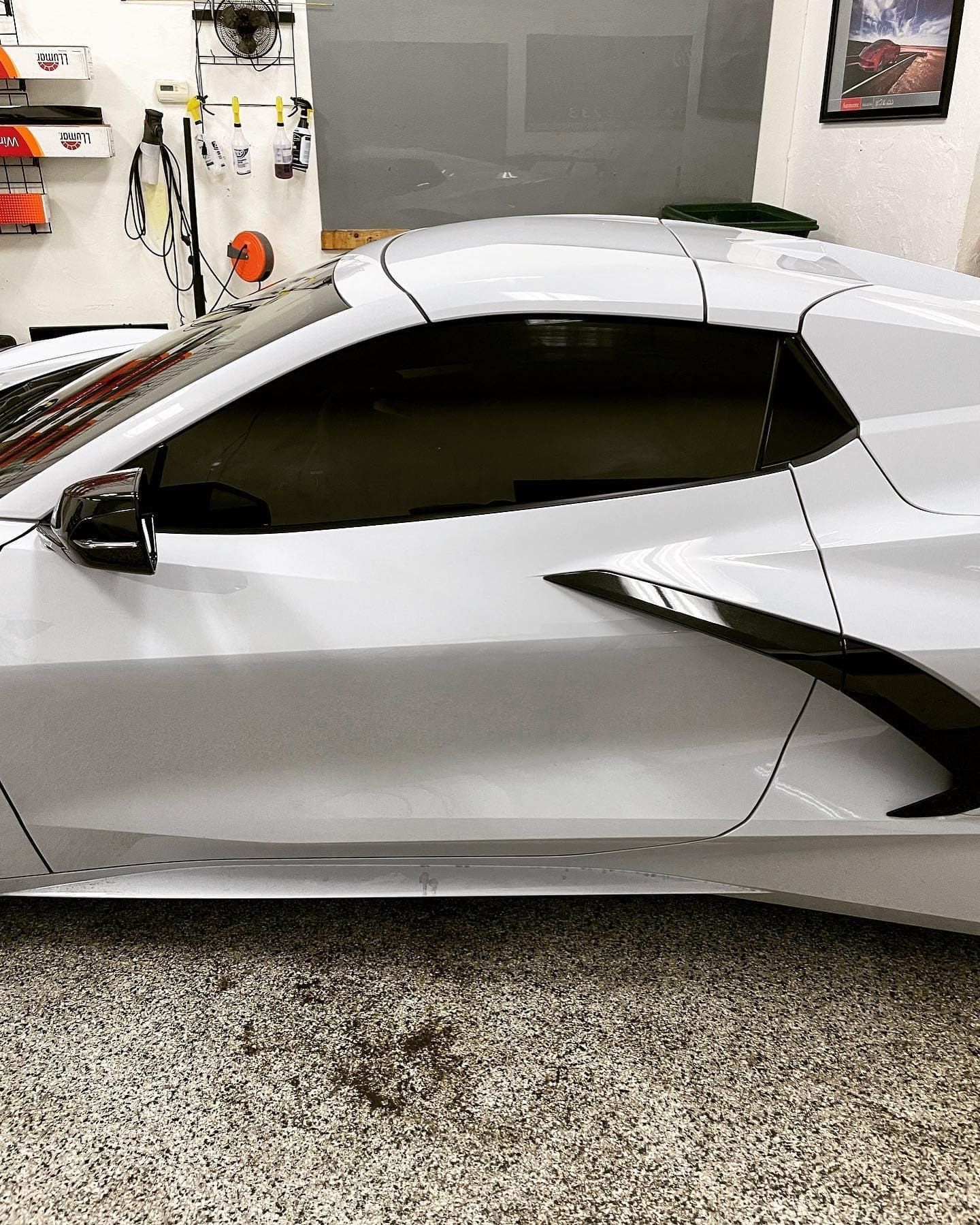 Silver sports car parked in a garage, side view with dark tinted windows.
