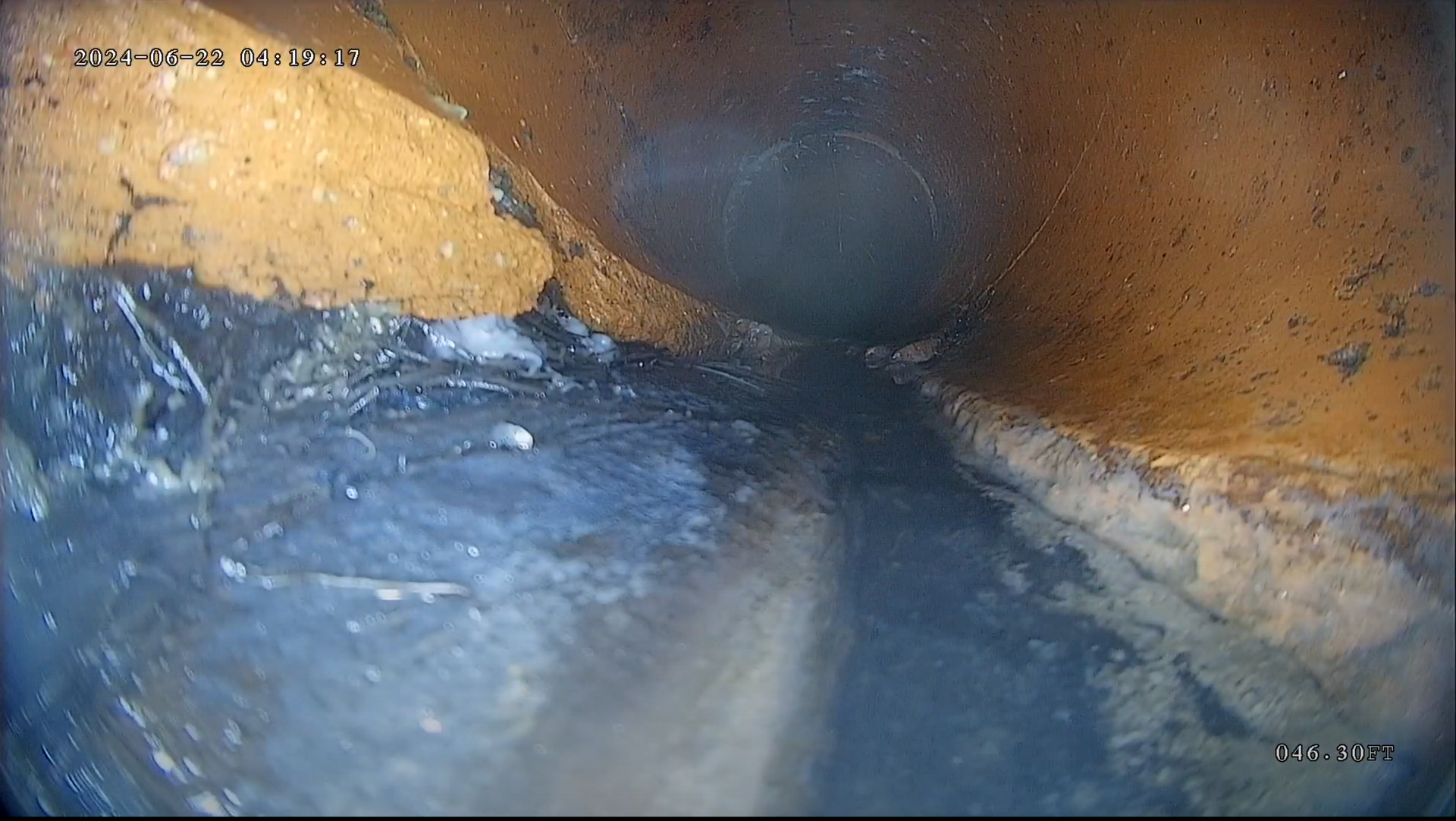A man is using a drain camera on a brick sidewalk.