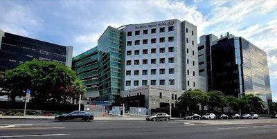 Modern office buildings along a city street with cars and trees