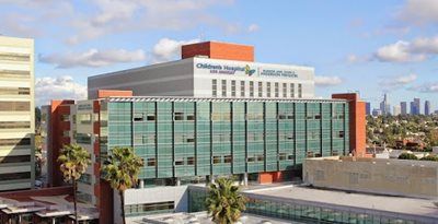 Hospital building with green-tinted windows and rooftop signage under a blue sky