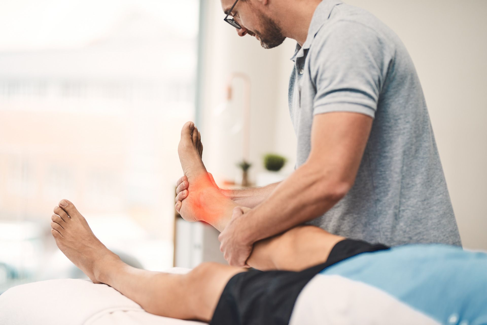 A man is giving a person a massage on their ankle.
