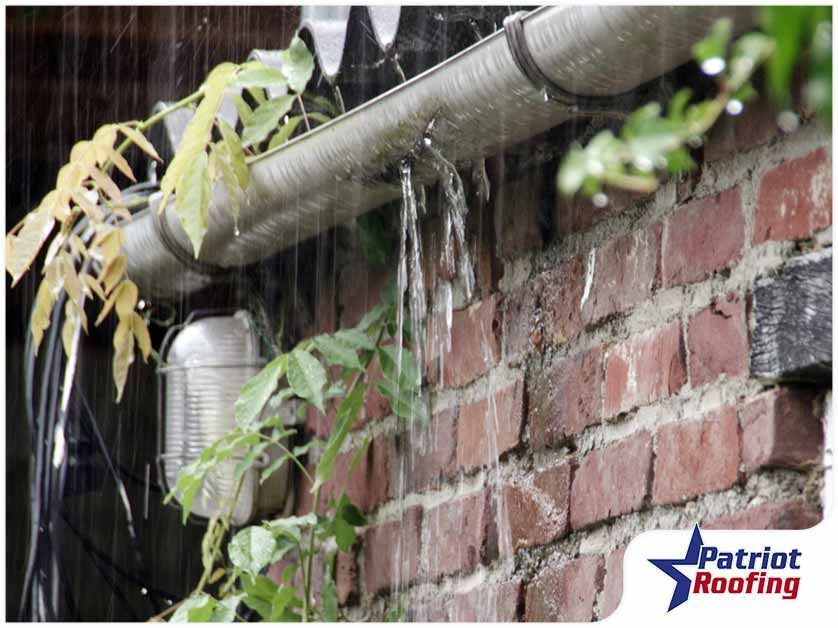 A gutter is leaking water on a brick wall.