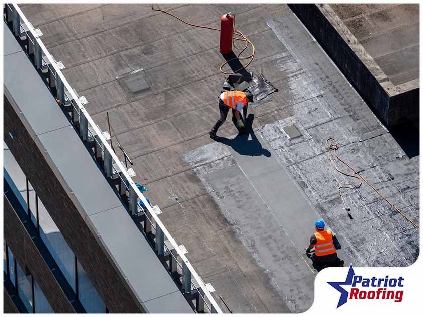 Two men are working on the roof of a building.