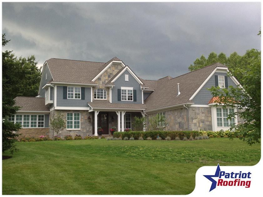 A large house with a patriot roofing logo in the corner