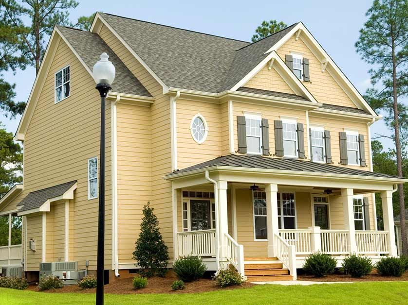 A large yellow house with a porch and a street light in front of it