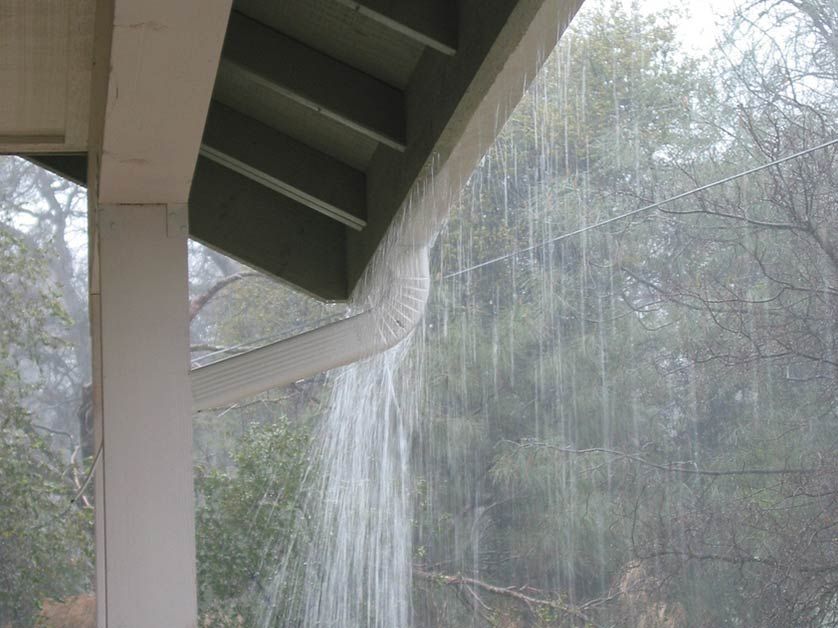 Rain is falling from the roof of a house.