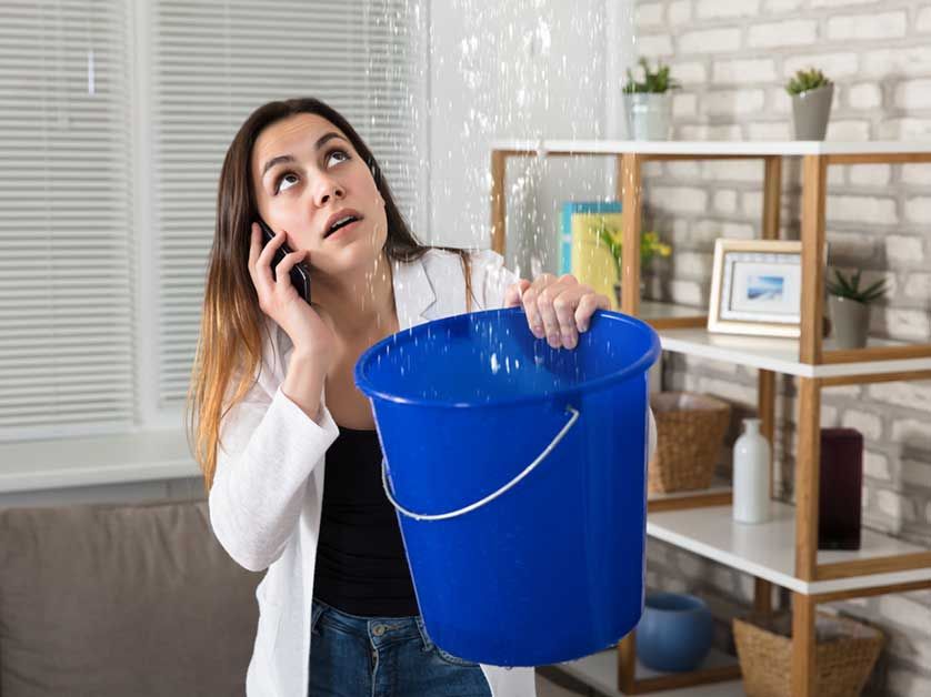 A woman is holding a blue bucket and talking on a cell phone.