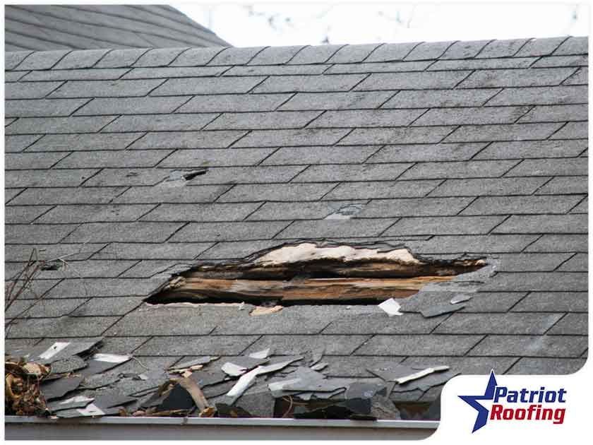 A roof with a hole in it and a patriot roofing logo in the corner.