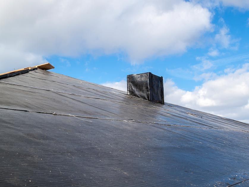 A roof with a chimney on it and a blue sky in the background.