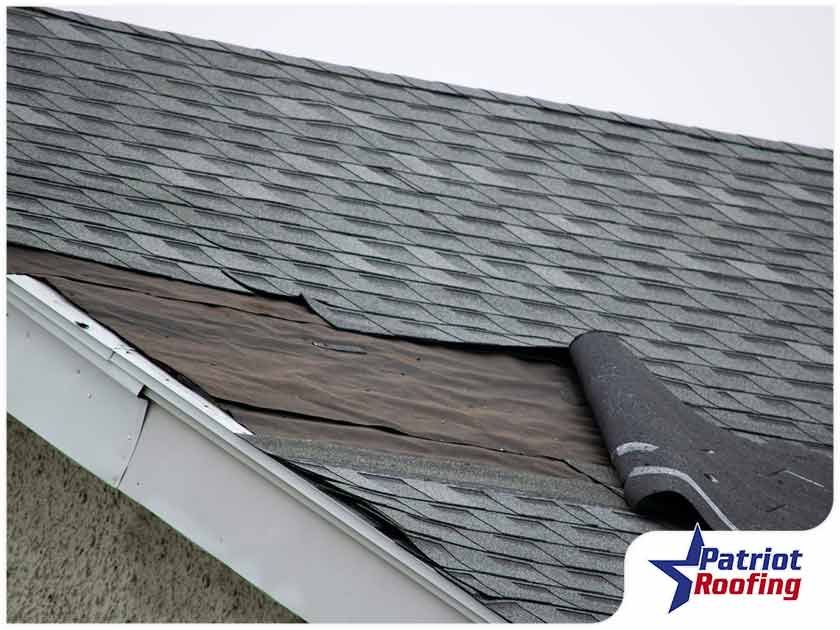 The roof of a house is being repaired by patriot roofing.