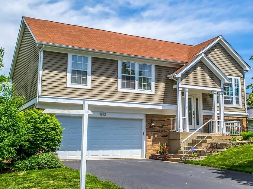 A large house with a blue garage door is for sale.