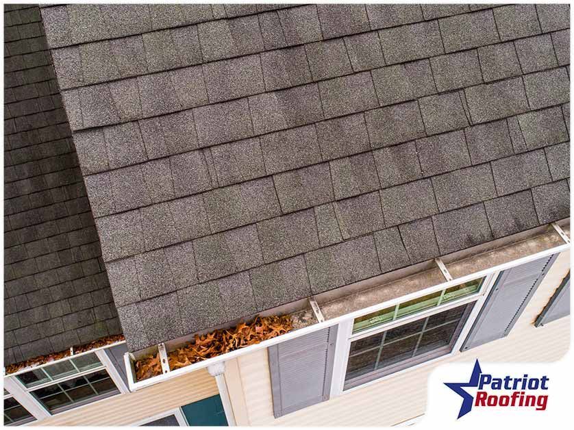 An aerial view of a roof of a house with a gutter filled with leaves.