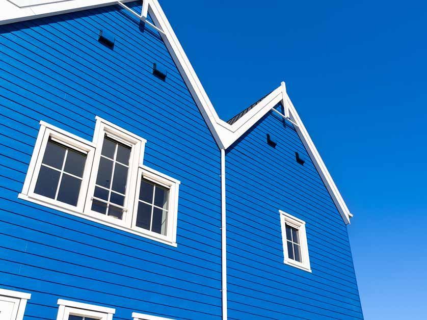 A blue house with white trim and windows against a blue sky
