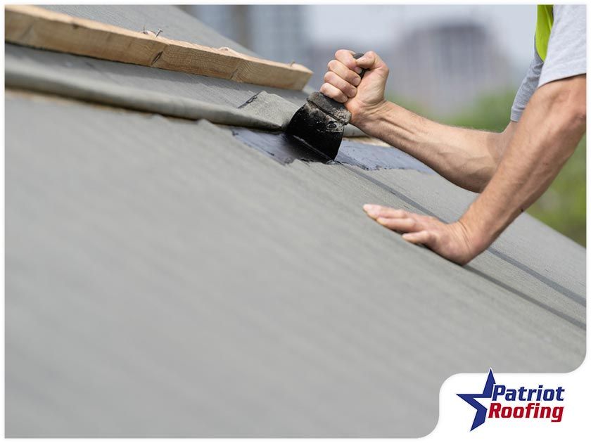 A man is painting a roof with a brush.