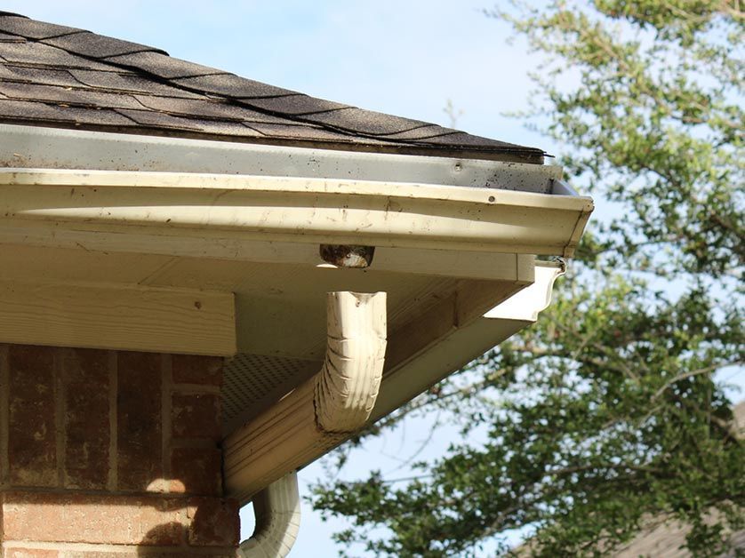 A close up of a gutter on the side of a house.