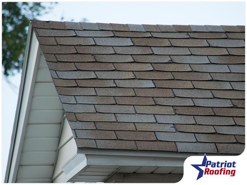 A patriot roofing logo is on the roof of a house