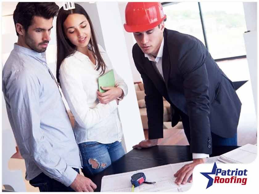 A man wearing a hard hat is talking to a woman and a man.