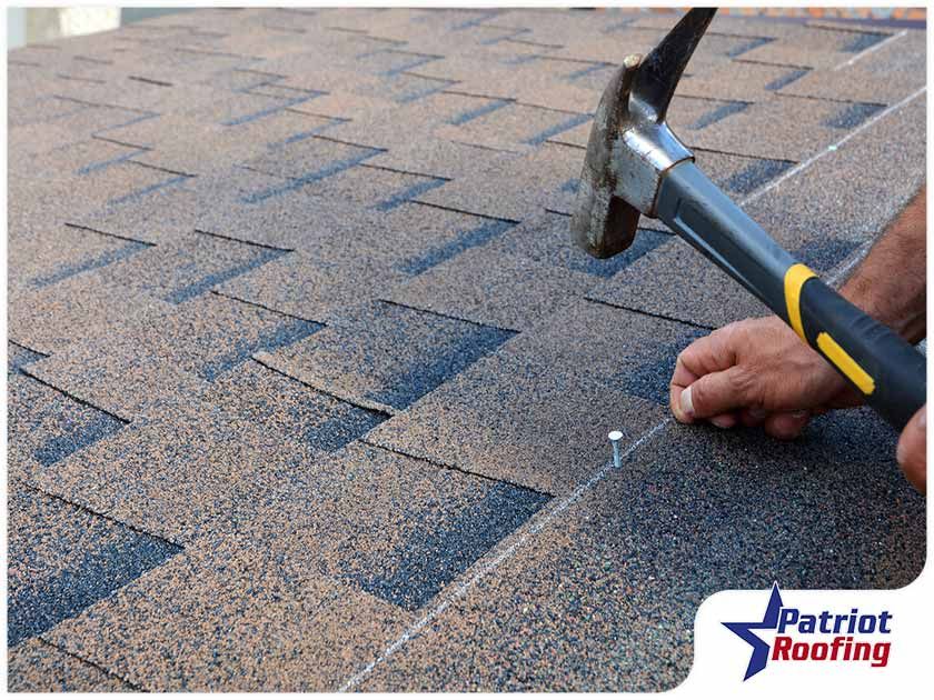A person is working on a roof with a hammer and nail.