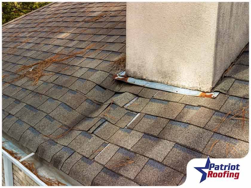 A chimney is sitting on top of a roof with shingles missing.