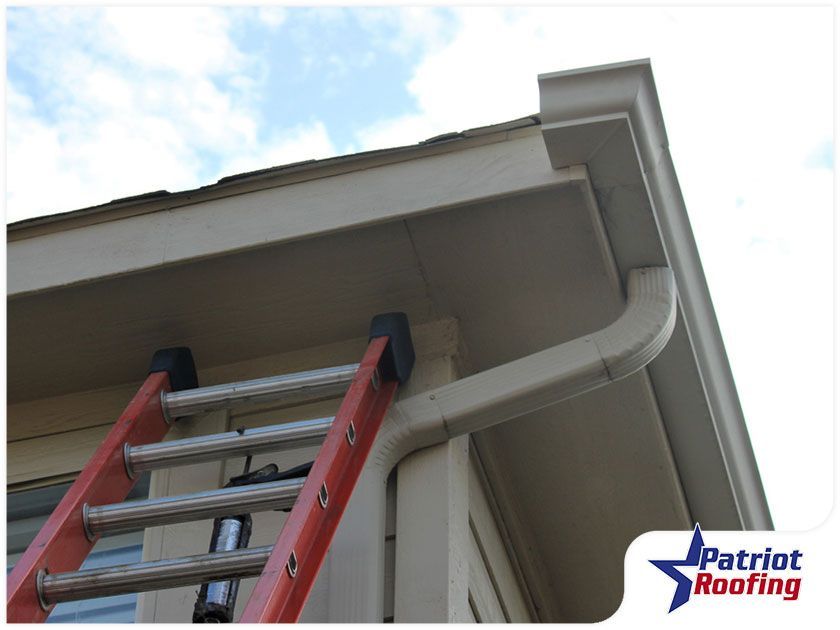 A ladder is attached to the side of a house by patriot roofing