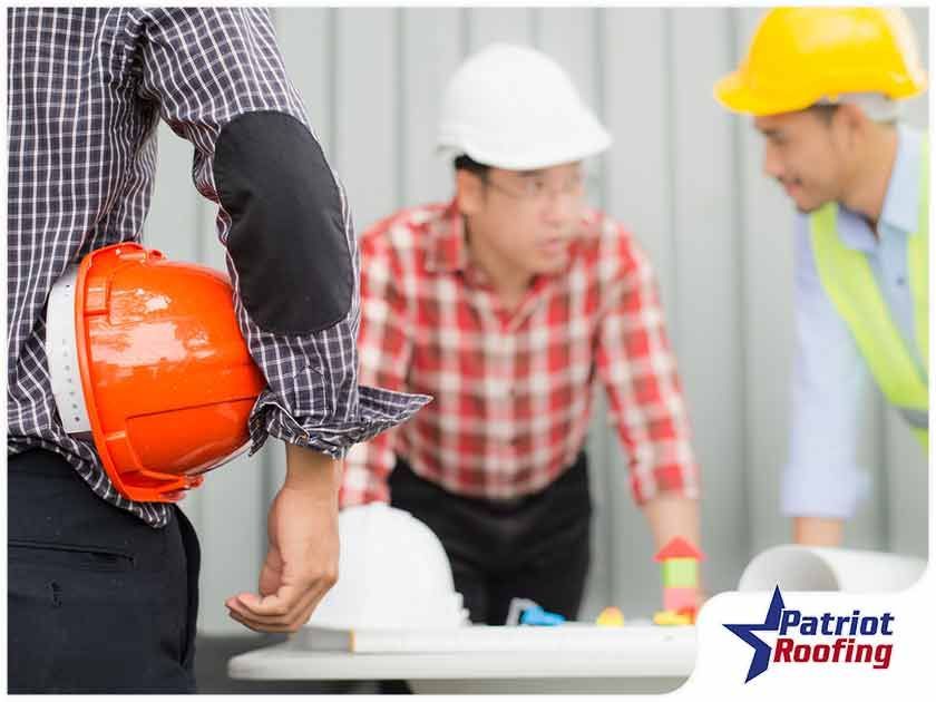 A group of construction workers wearing hard hats are standing around a table.