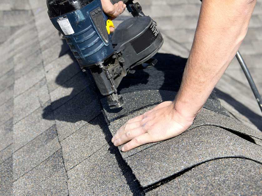 person nailing roof tiles down