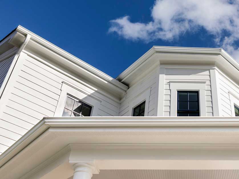 The roof of a white house with a blue sky in the background.
