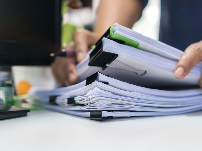 A person is holding a stack of papers on a desk.