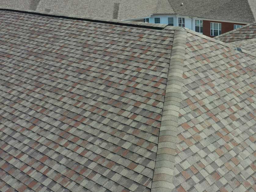 A close up of a roof with a house in the background