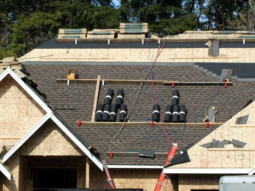A roof is being installed on a house under construction.