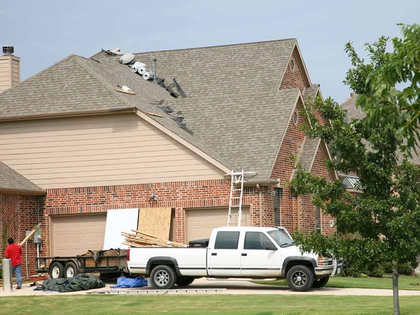 A white truck is parked in front of a brick house