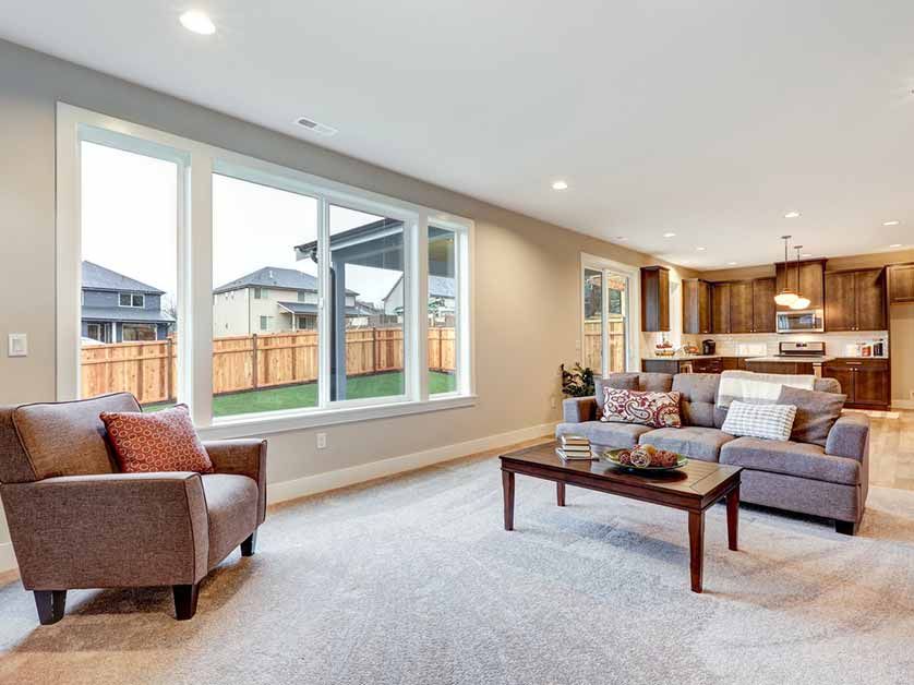 A living room with a couch , chair , coffee table and large windows.