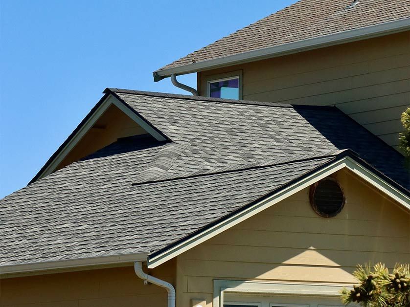 A house with a gray roof and a blue sky in the background