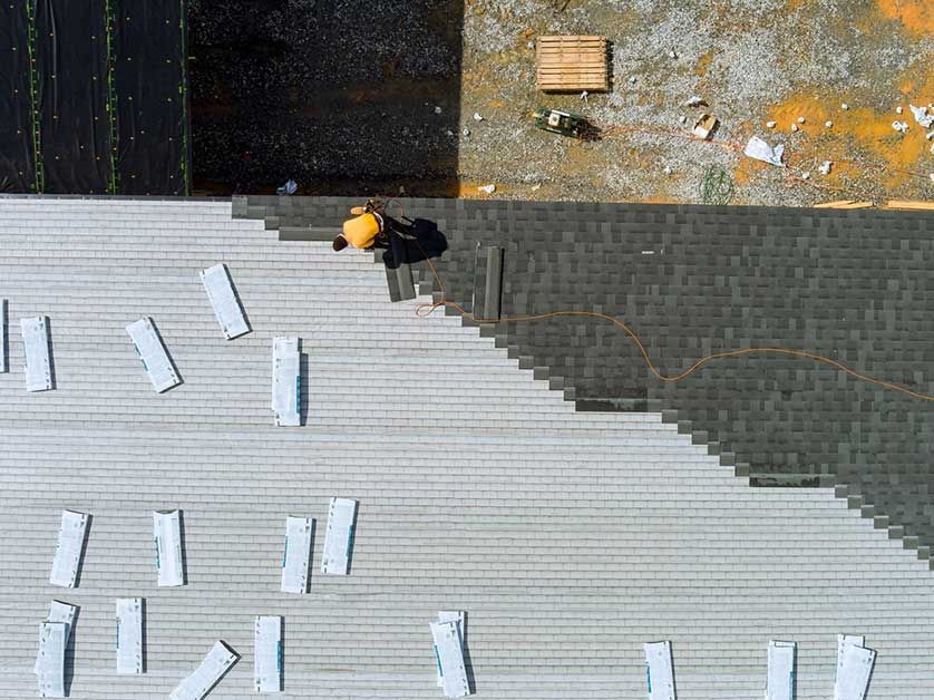 An aerial view of a construction worker installing a roof.