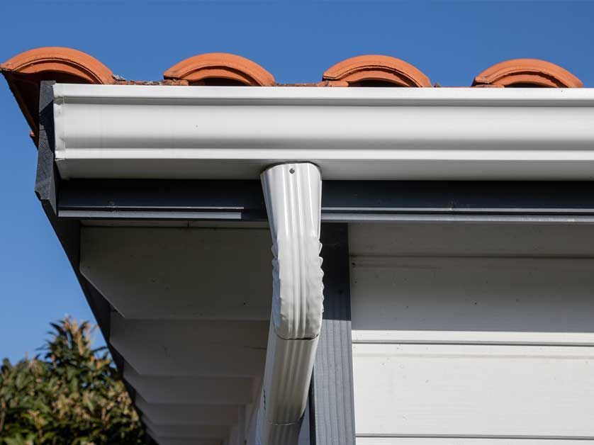 A close up of a gutter on the side of a house.