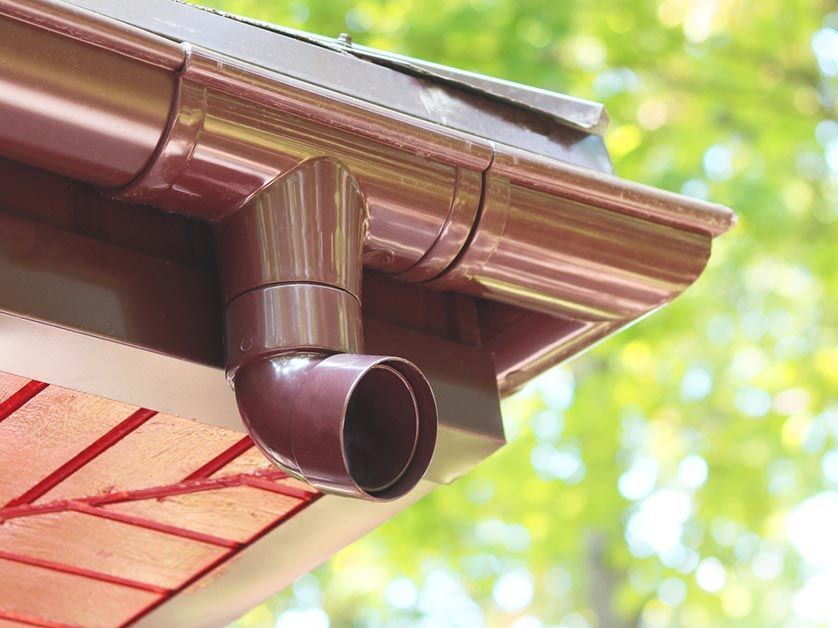A close up of a brown gutter on the roof of a house.