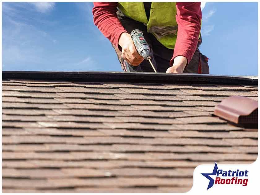 A man is working on a roof with a drill.