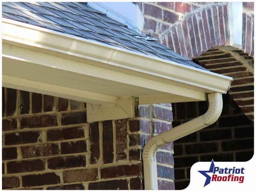 A picture of a gutter on a brick building with patriot roofing in the corner