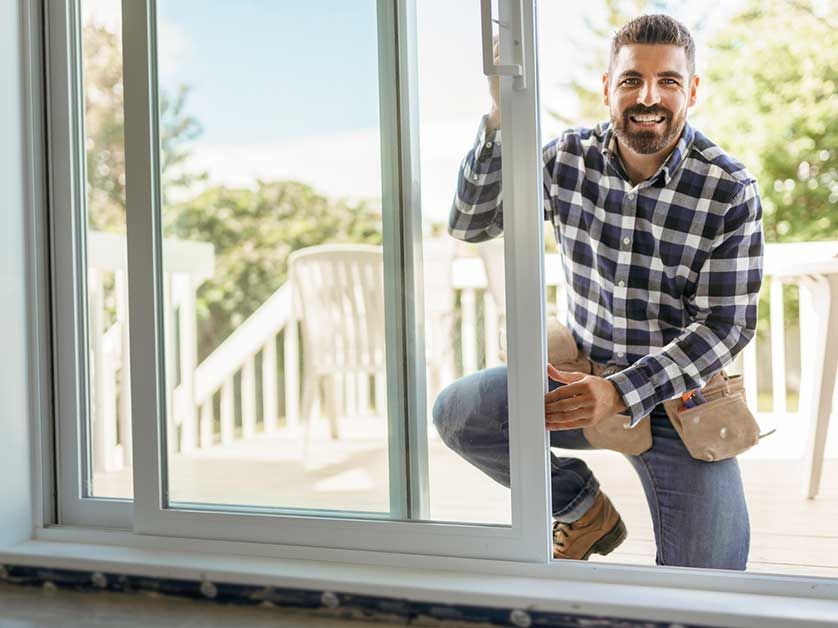 A man is installing a sliding glass door in a house.