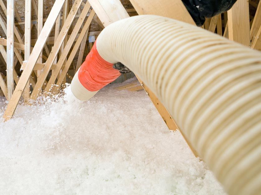 A hose is being used to blow insulation into an attic.