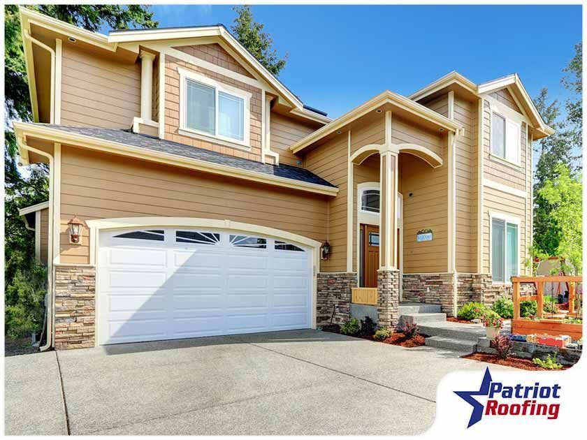 A large house with a white garage door and a patriot roofing logo
