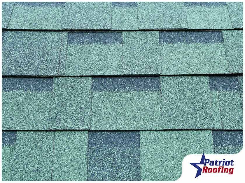 A close up of a roof with a patriot roofing logo in the corner