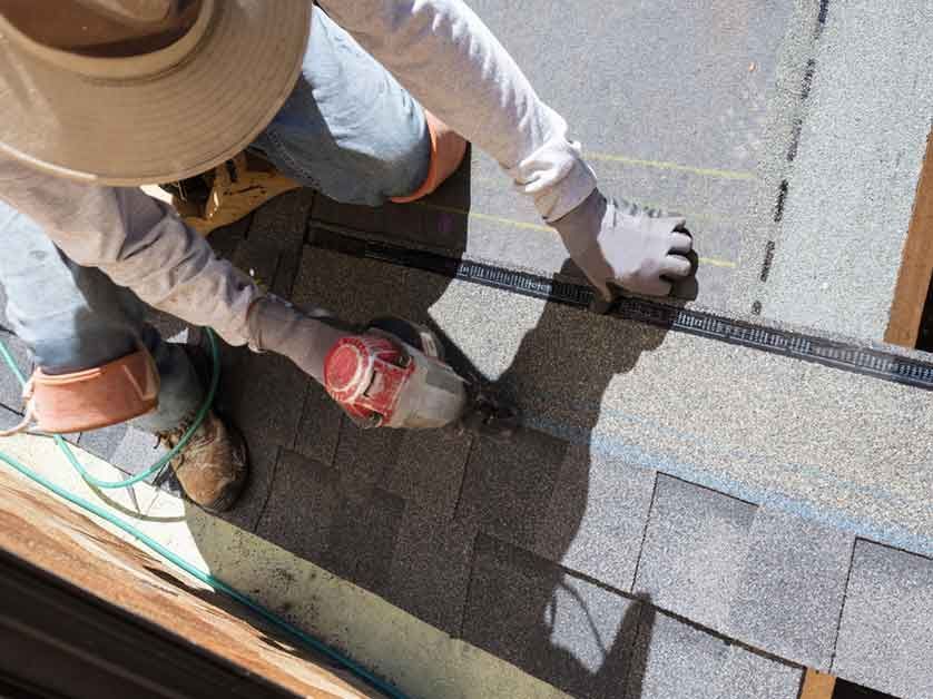 A man is measuring a roof with a tape measure.