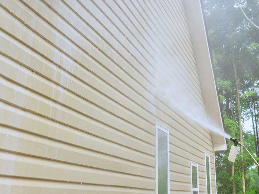 A house is being cleaned with a high pressure washer.