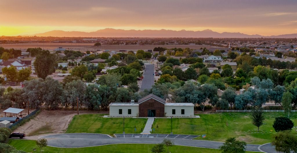 A wide-angle sunset view overlooking a building with a central brick entrance set before a suburban landscape and hills.