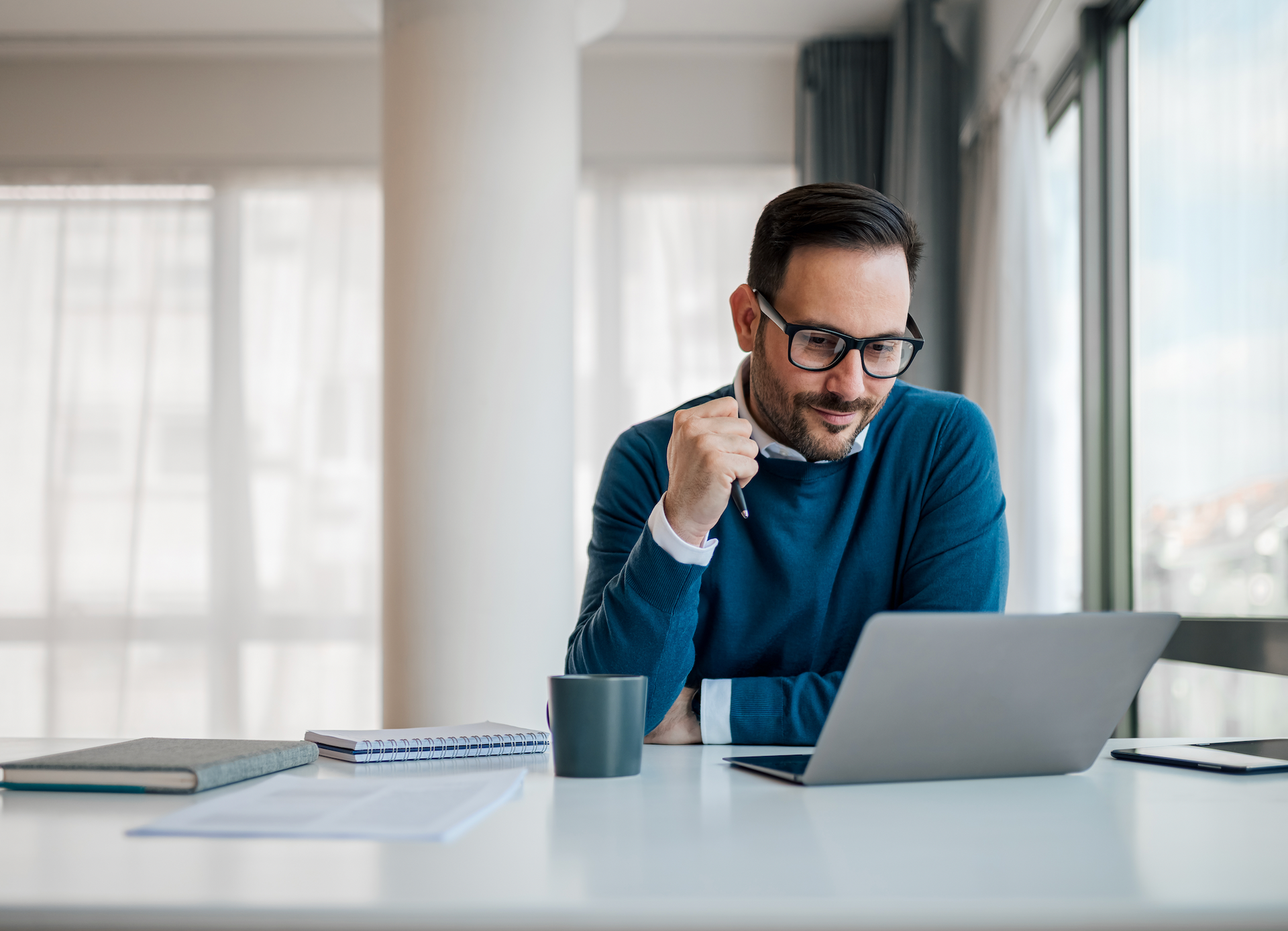 A man is sitting at a desk using a laptop computer.