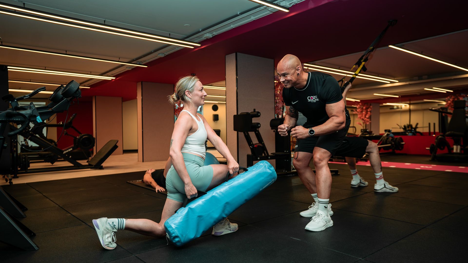 Een persoon in sportkleding tilt een halter boven zijn hoofd in een sportschool.