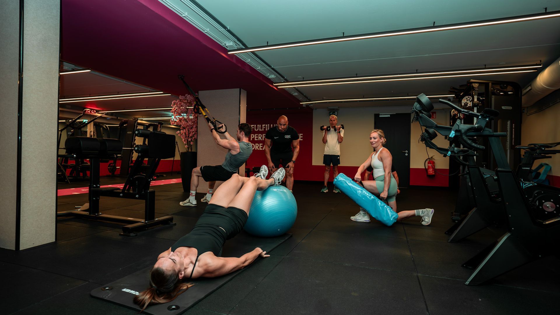 Persoon in een felgele top die een halter squat uitvoert in een sportschool.