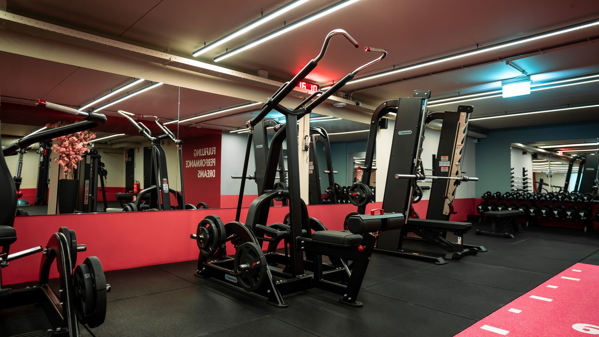 Fitnessapparatuur met een hometrainer en kabelmachines in een trainingsruimte.